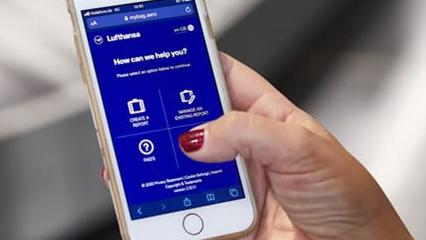 Hand holding mobile phone displaying Lufthansa app.