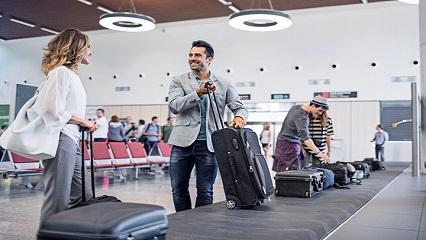 Passengers collecting luggage from airport baggage carousel