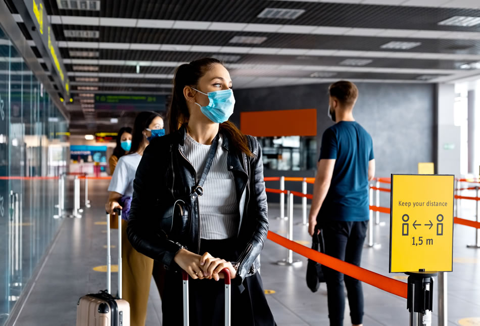 Passengers in airport queue following pandemic control measures (physical distancing, mask wearing)